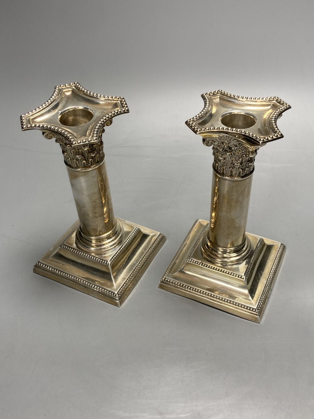 A pair of late Victorian silver dwarf candlesticks, Henry Matthews, Birmingham, 1895, 14.2cm, weighted.